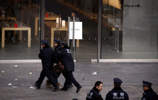 A woman is dragged away by police after she refused to leave from the front of the Apple store in the Beijing district of Sanlitun